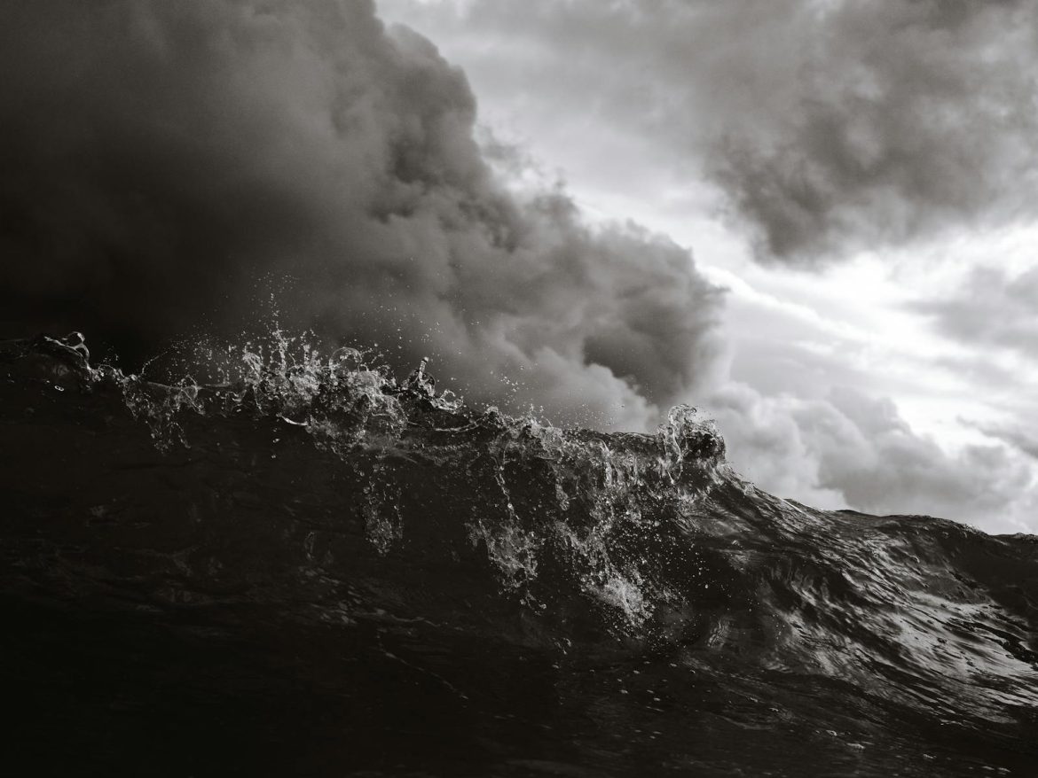 A dramatic black and white photo capturing stormy waves against dark clouds at Bondi Beach.