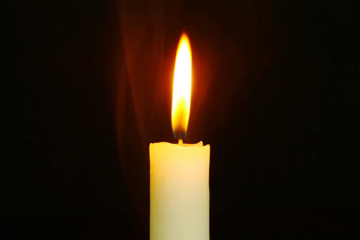 A single candle burning brightly in the dark, symbolizing light and hope.