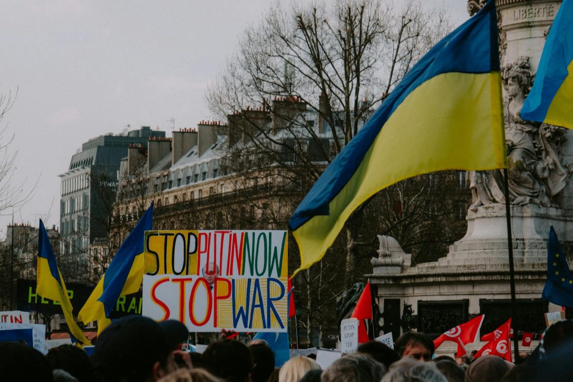 A dynamic crowd in Paris rallies with Ukrainian flags and anti-war signs, advocating peace.