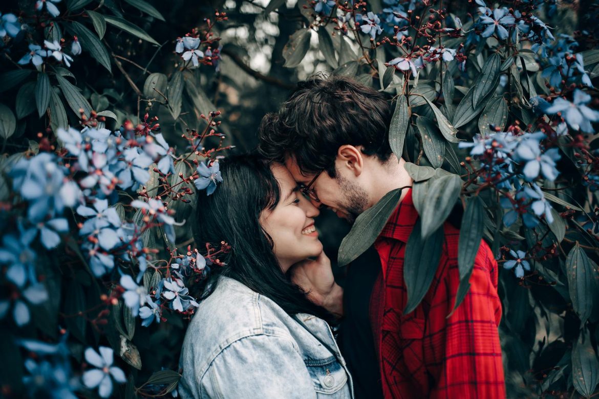 Happy couple sharing a romantic moment surrounded by beautiful blue flowers.