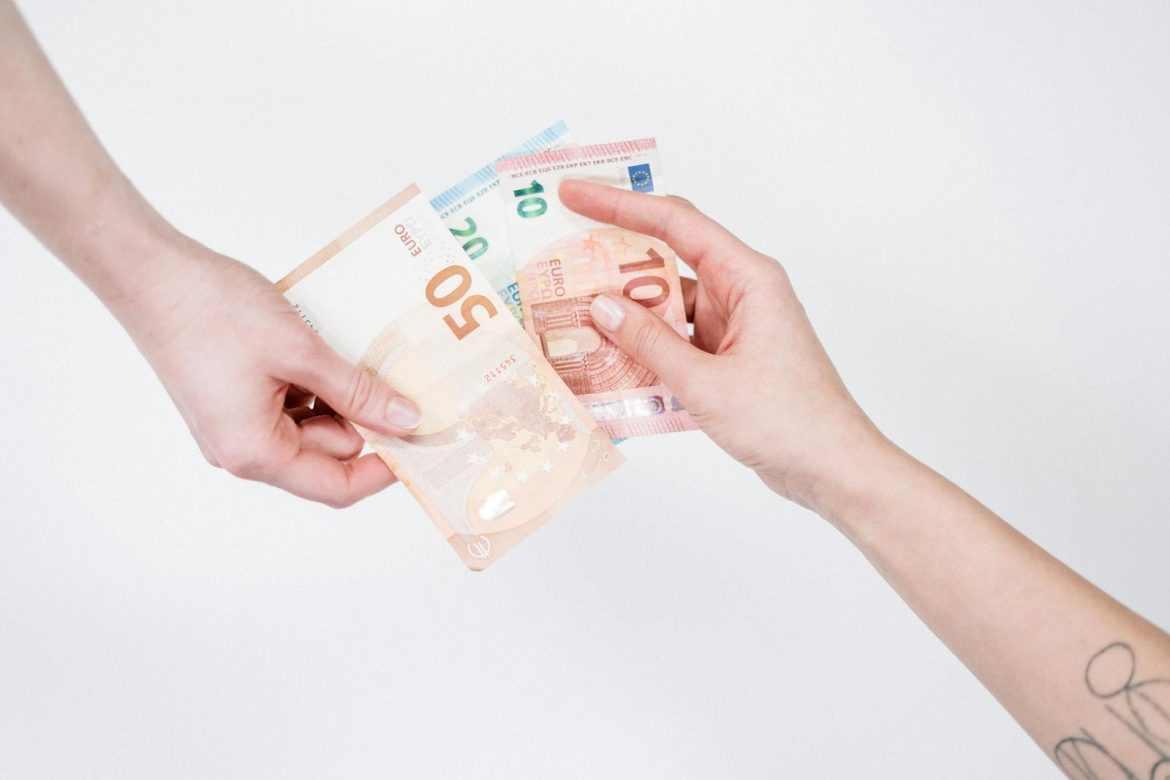 Close-up of hands exchanging euro banknotes, symbolizing financial transactions and currency exchange.