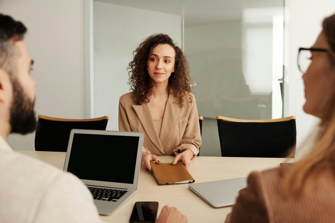 A woman in a business suit participates in a job interview, showcasing professionalism and modern office environment.