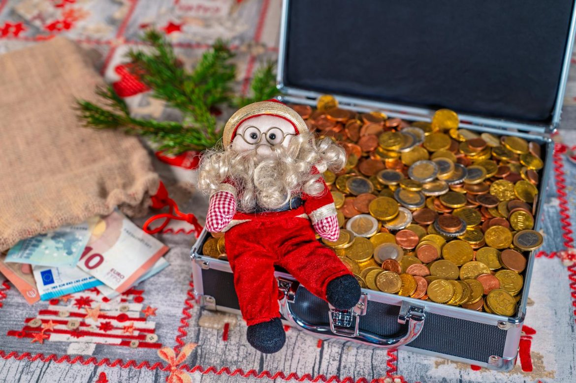 Small Santa figurine with euro coins and Christmas decorations in a festive setting.