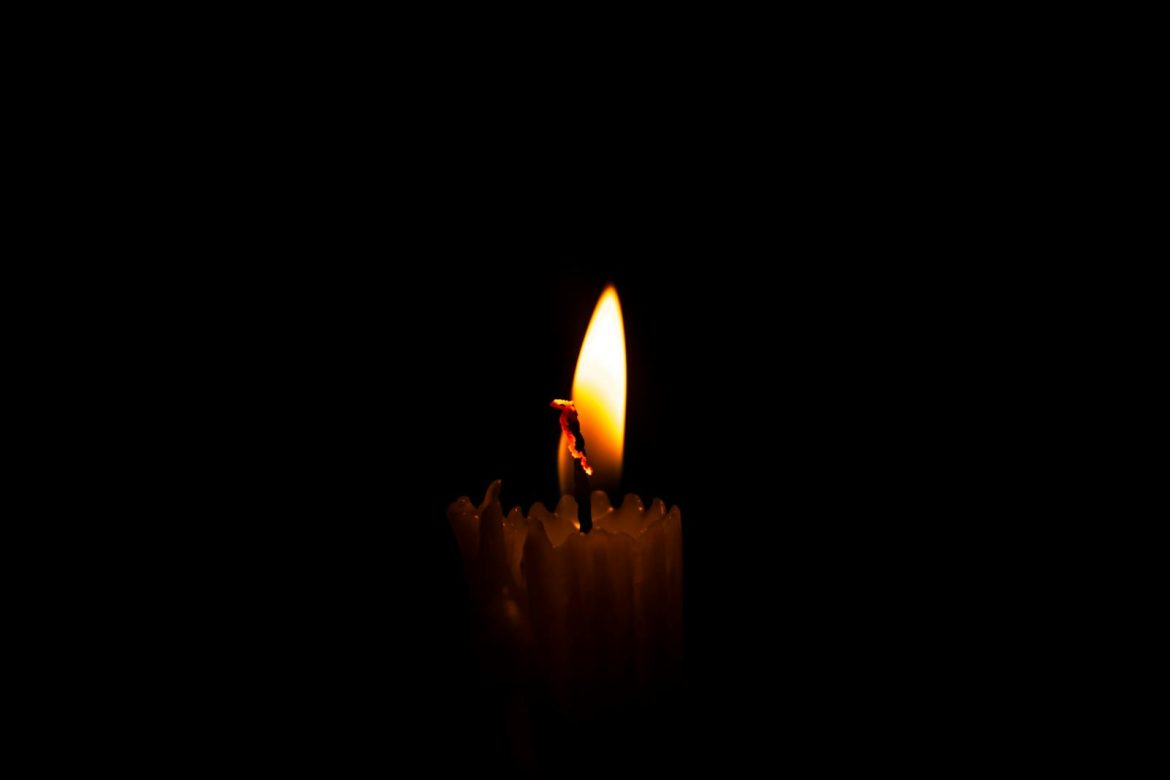 A serene close-up of a burning candle against a dark, moody background, capturing stillness and warmth.