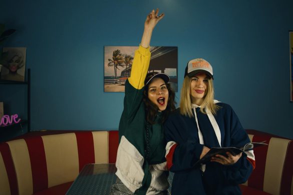 Two stylish women celebrating with joyful expressions inside a retro diner.