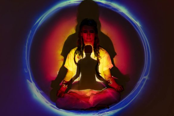 A woman in meditation surrounded by colorful auric light, creating a spiritual atmosphere.