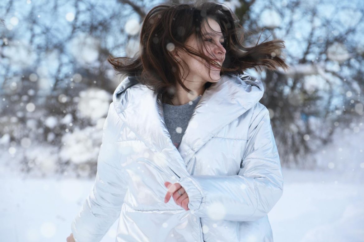 Young woman enjoying a joyful winter day outdoors with snowflakes around her.