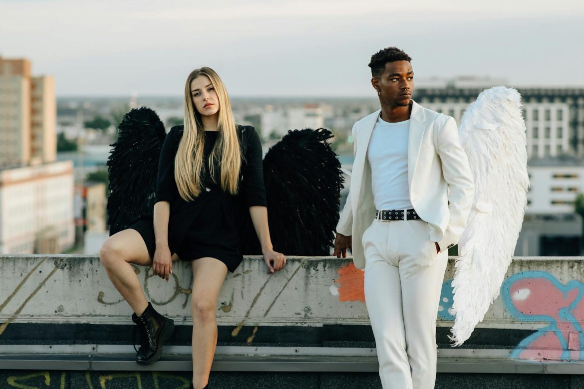 A man and woman dressed as angels on a rooftop, showcasing black and white contrast.
