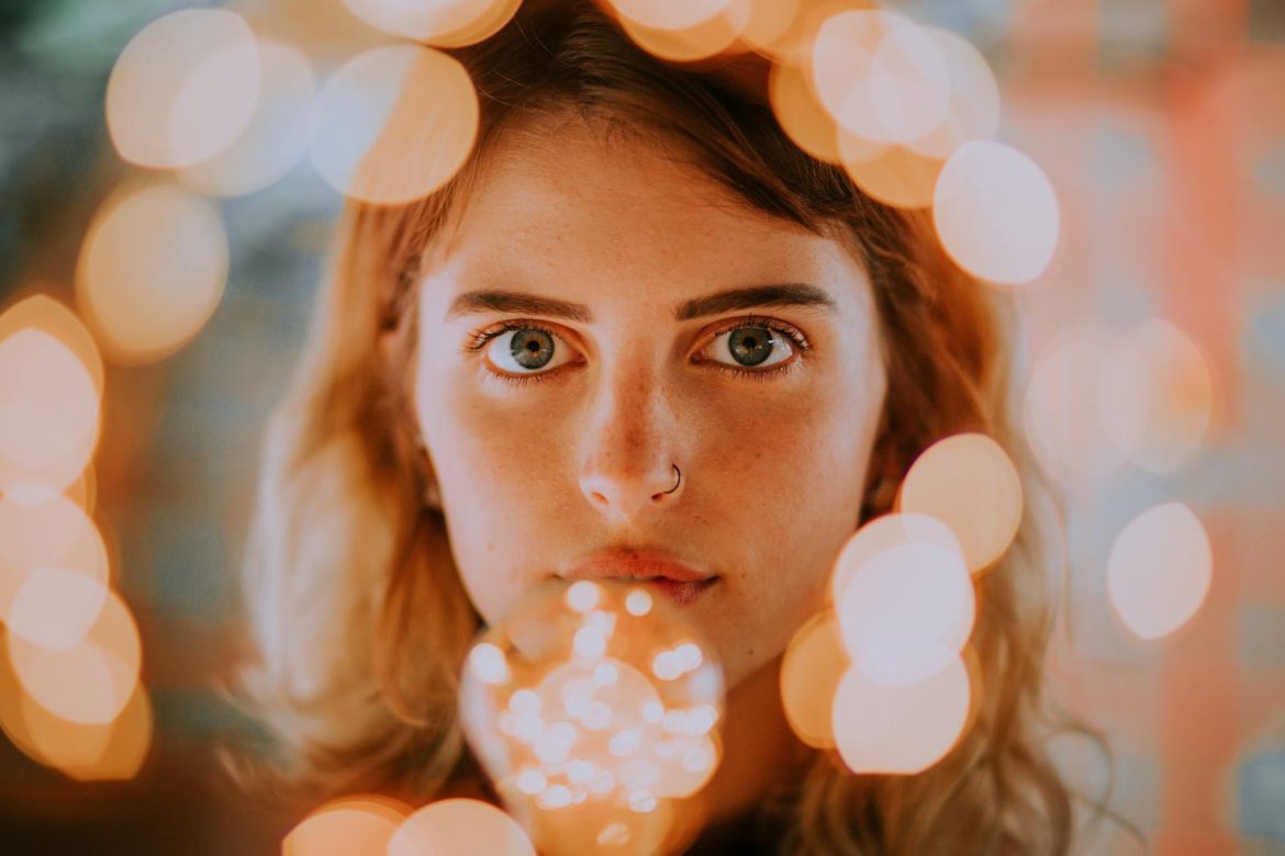 Close-up portrait of a woman with captivating bokeh light effects enhancing her gaze.