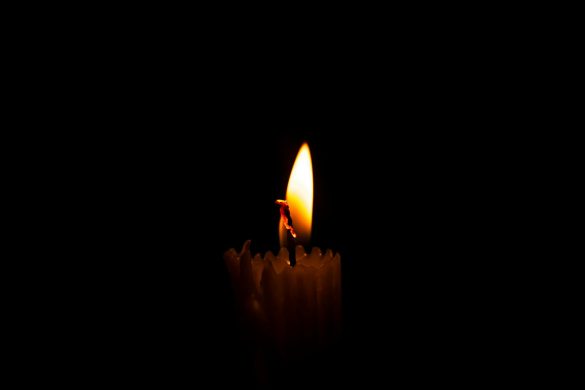 A serene close-up of a burning candle against a dark, moody background, capturing stillness and warmth.