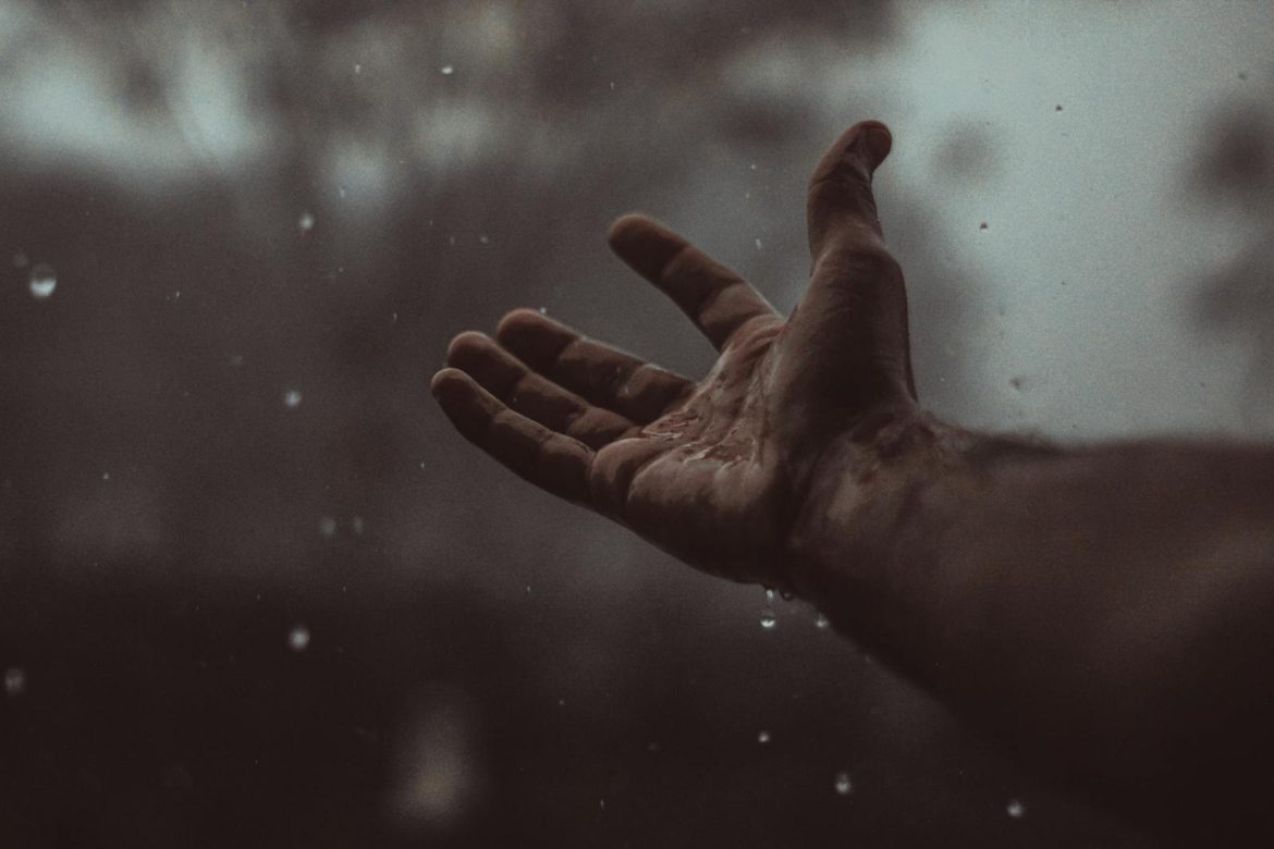 A close-up of a hand catching raindrops in Bahawalpur, embracing the rain's refreshing feel.