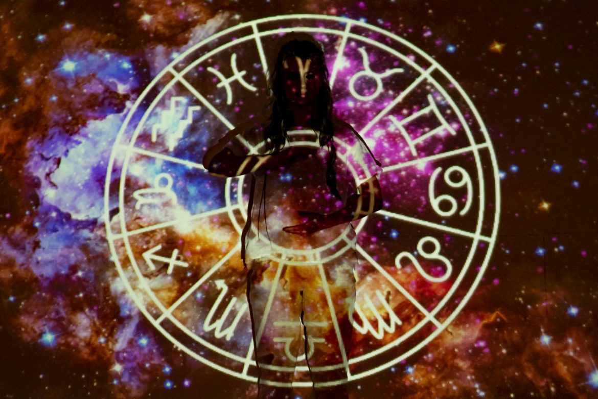 Woman standing with astrological symbols projected, evoking a mystical vibe.
