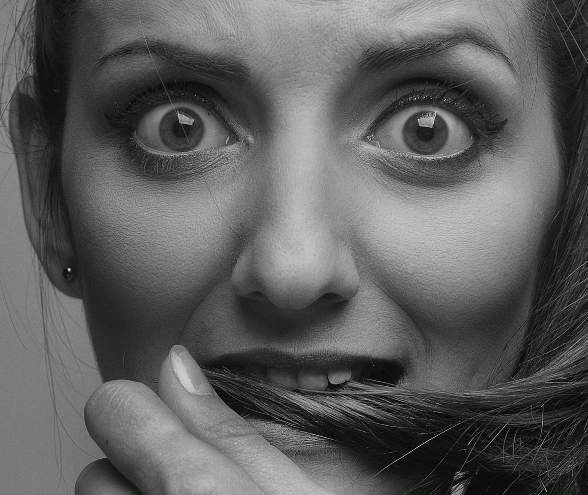 Expressive black and white close-up portrait depicting a worried woman holding her hair.