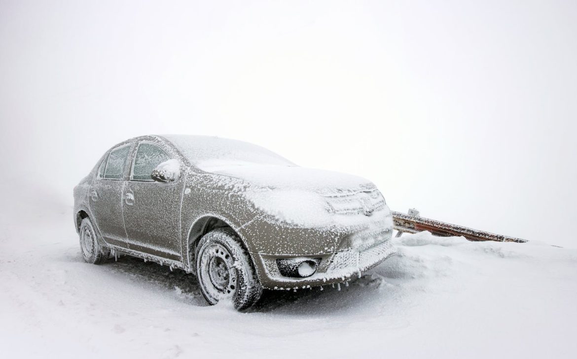 A sedan covered in snow and ice parked in a frosty winter setting, illustrating cold weather extremes.