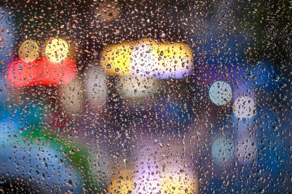 Raindrops on a window with vibrant city lights bokeh in Tân Bình, Vietnam.