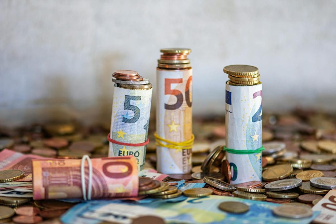 Close-up of rolled Euro banknotes and coins on a table, symbolizing finance and savings.