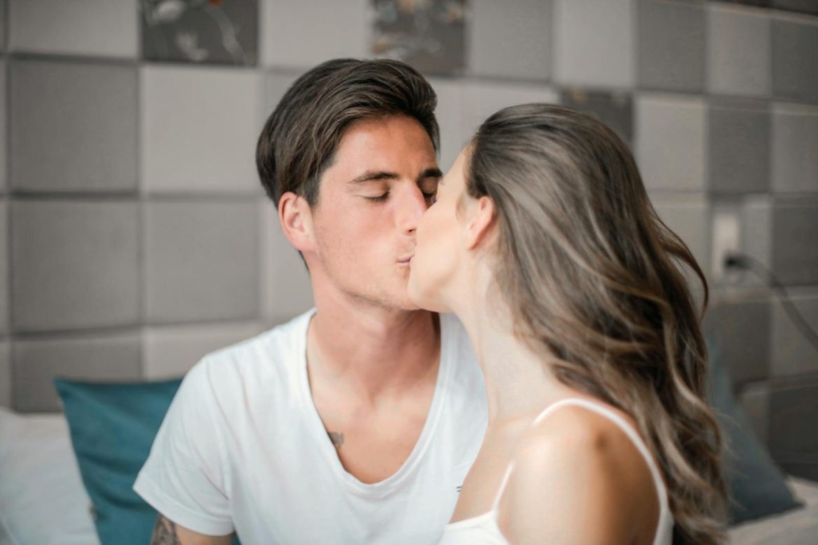 A couple intimately sharing a kiss in a cozy bedroom environment, capturing love and togetherness.