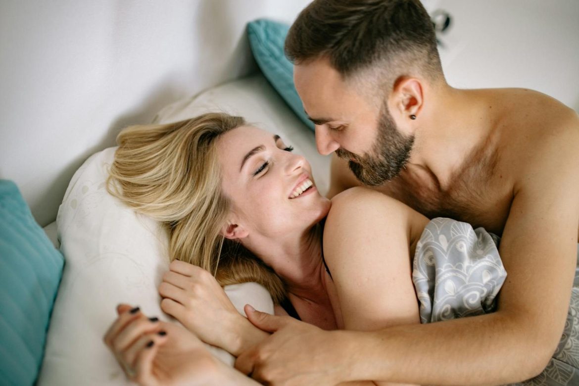 A joyful couple embracing in bed, depicting warmth and intimacy.