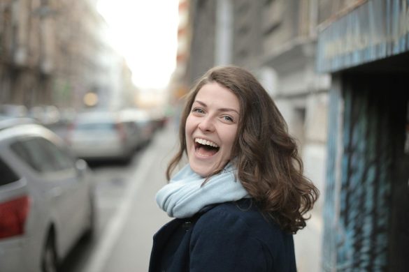 Portrait of a happy woman with a scarf, smiling in an urban street setting.
