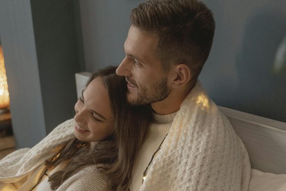 Couple enjoying a cozy moment under a blanket, showcasing warmth and love indoors.