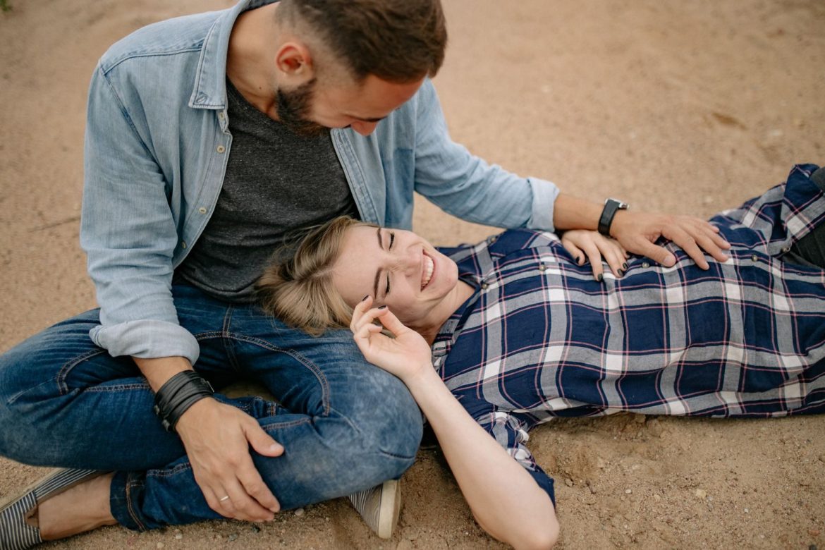 A joyful couple enjoying a relaxed moment on a sandy beach.