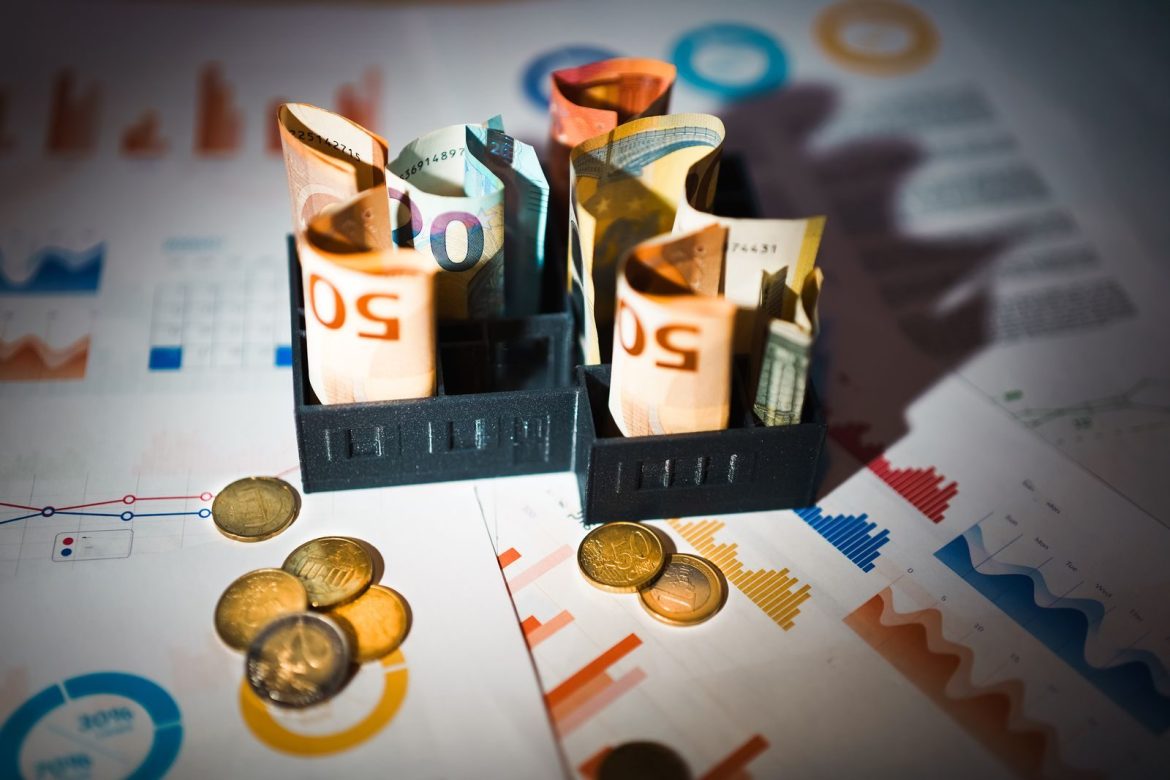 A close-up of euro banknotes and coins on top of financial charts symbolizing investment and economic analysis.