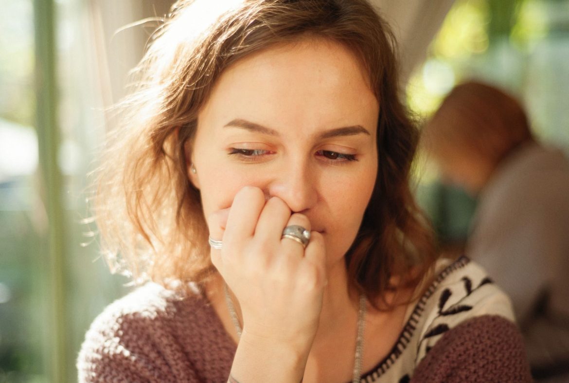 Thoughtful young woman posing indoors with hand on face.