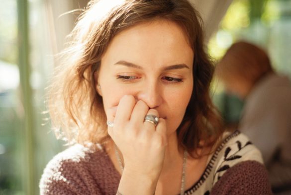 Thoughtful young woman posing indoors with hand on face.