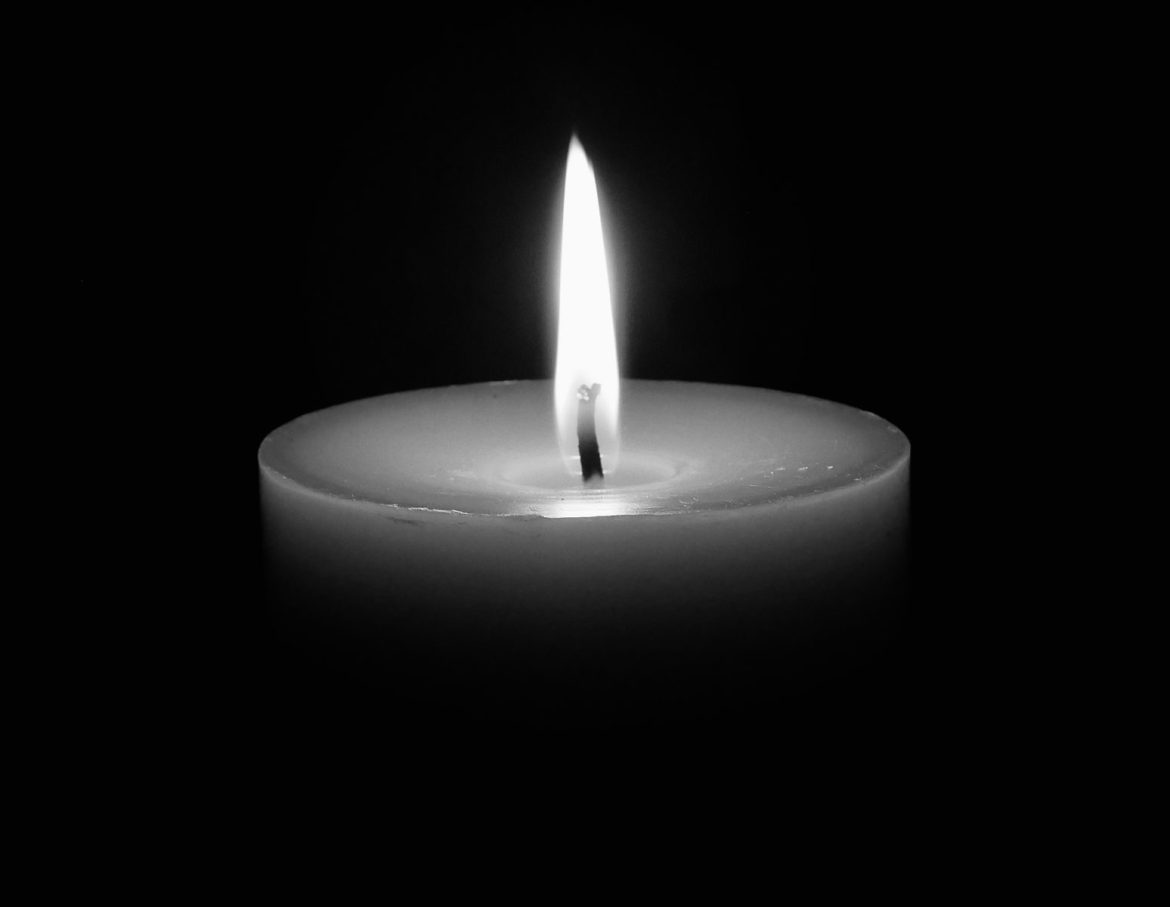 A calming image of a single candle flame glowing in the dark, offering serenity.
