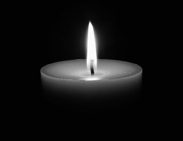 A calming image of a single candle flame glowing in the dark, offering serenity.