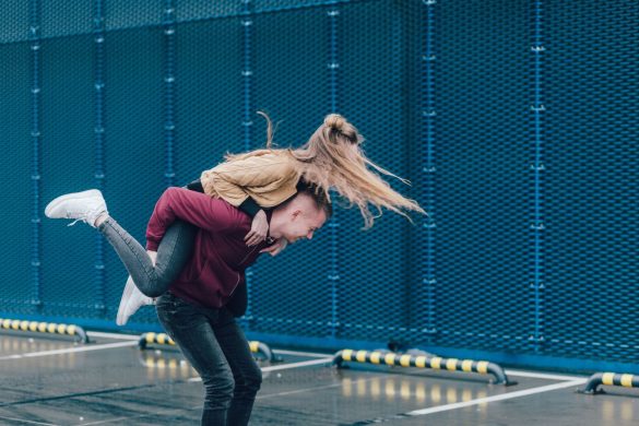 Young couple enjoys a playful piggyback ride in an urban setting, embodying fun and togetherness.