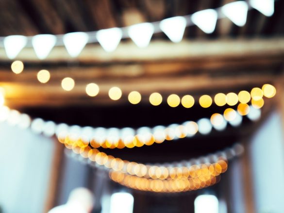 White triangular bunting flags hanging above strings of glowing golden bokeh lights